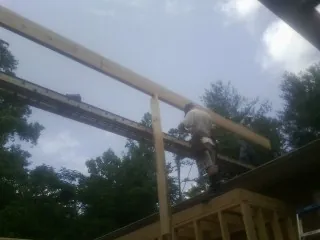 Carpenter setting a ridge beam over a new addition frame — Ice Dam Removal by Roofing Brothers in Saucier