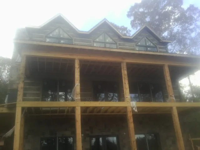 Dormers and porch framing on a large log home under construction — Roof Coating work by our crew in Saucier