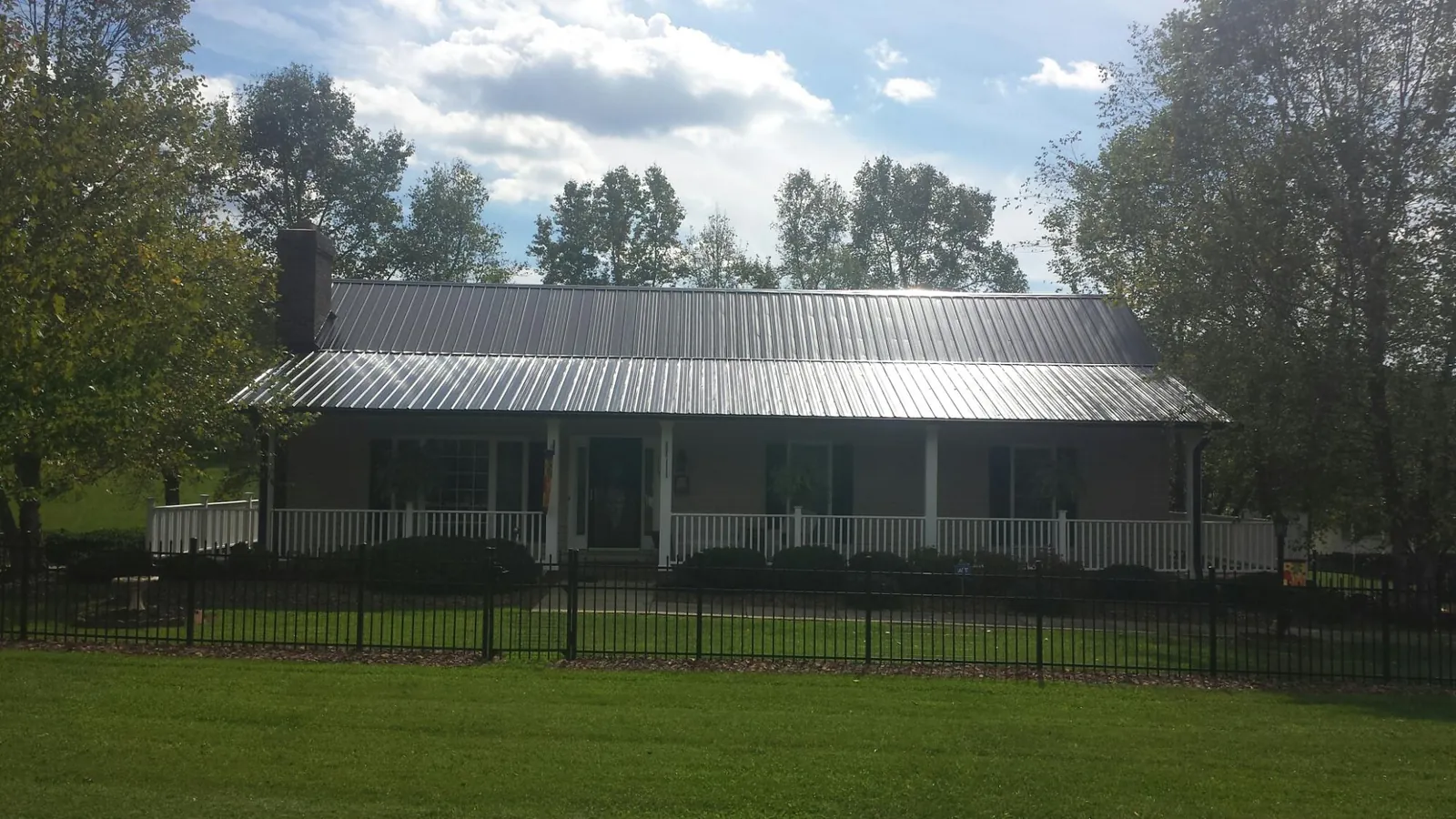 Gray metal roof on a brick ranch with a full width front porch — Gutter Guard Installation work by our crew in Saucier
