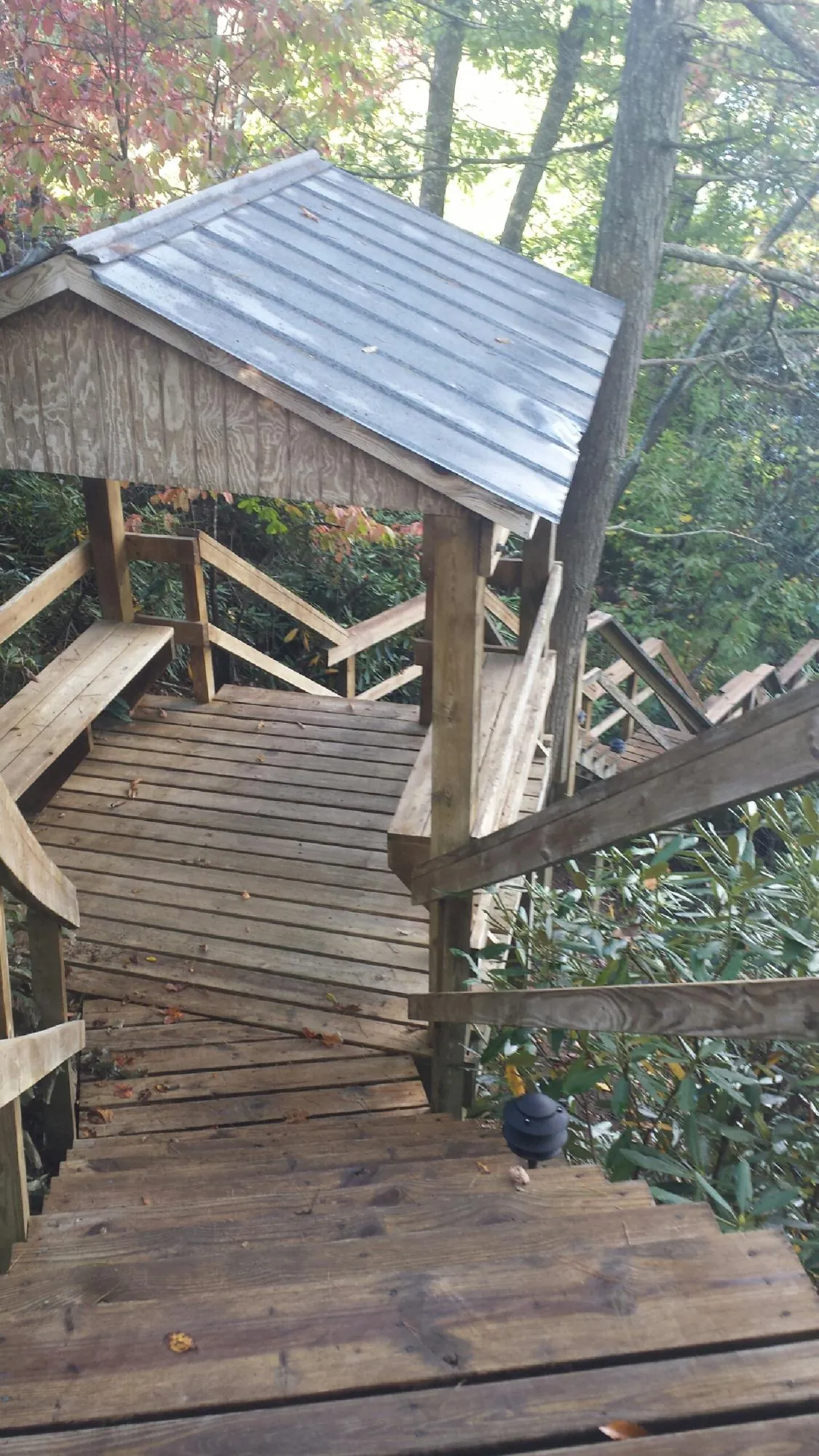 Metal roofed shelter over wooden steps on a wooded walkway — Skylight Repair & Installation work by our crew in Saucier