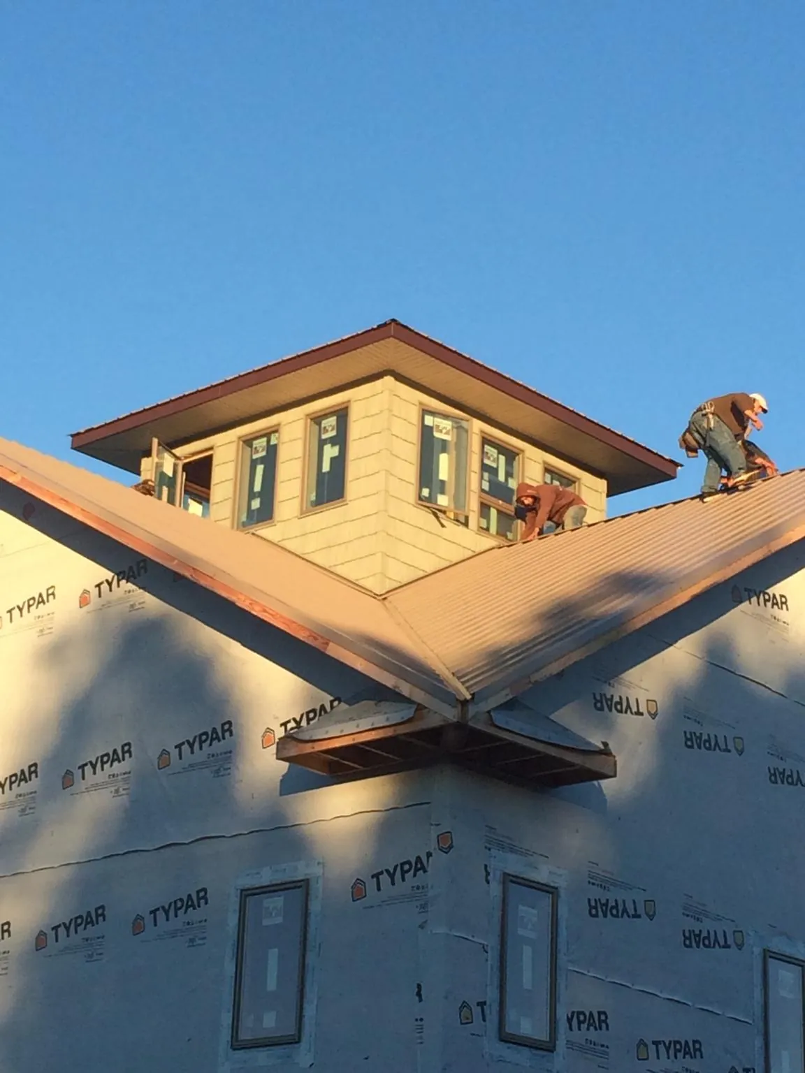 Roofers working around a rooftop cupola on a new metal roof at sunset — Roof Waterproofing in Saucier by Roofing Brothers